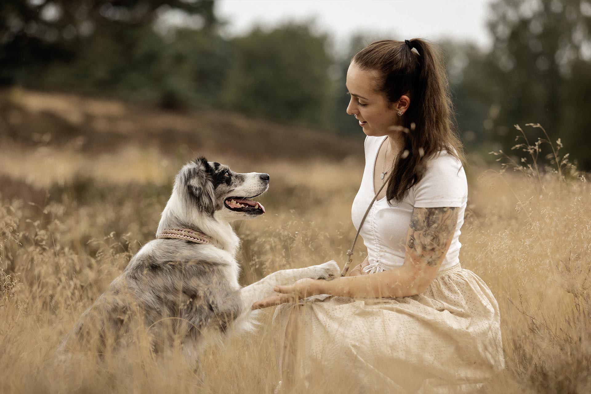 Hundetrainerin Sara Maggiorelli von Team Spirit mit Hündin Yuna im Feld sitzend.